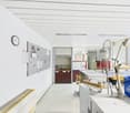 Laboratory space with white walls, white ceiling, clock, noticeboard, worktables, equipment, chairs, trash bin