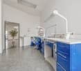 modern office room, white walls, gray floor, blue cabinets, white countertops, medical equipment, sink, plant