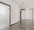 Empty room with white walls, gray tiled floor, two doors, one with a silver handle, and a sign on the wall.