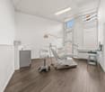 Empty room with dental chair, sink, monitor, and windows