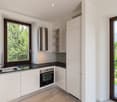 modern kitchen with built-in appliances, white cabinets, marble countertops, large windows, balcony