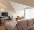 spacious living room, large couch, wooden floor, white walls, windows, glass table, TV