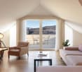 modern living room with balcony, wood floors, pink sofa, brown chairs, coffee table, view of mountains