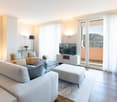 Large sofa, coffee table, TV, floor lamp, double glass doors to balcony