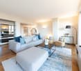 modern design, large couch, coffee table, ottoman, floor lamps, window with curtains, rug