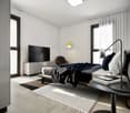 Spacious bedroom with white walls, large windows, hardwood floors, a king-size bed with navy blue bedding, a TV console, and a comfortable armchair.