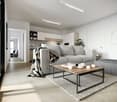 Spacious living room with gray sofa, wooden coffee table, and area rug. Shelving unit and kitchen visible in the background. Large windows and bright, open layout.