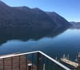 Balcony with metal railing overlooking a lake with mountains in the background