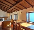 exposed wooden beams, wooden dining table, wooden cabinet, fireplace, radiator, chair, couch, lamp