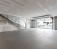 Empty garage with concrete floor, metal staircase, and open garage door.
