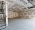 Empty garage with unfinished walls and ceiling, metal staircase