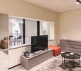 modern living room with large windows, flat screen TV, telephone, ottoman, coffee table, sideboard, carpet