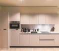 modern kitchen with white cabinets, black countertops, built-in oven, sink, and dishwasher