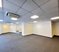 Empty room with ceiling air conditioning, white walls and carpeted floor