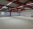 Large open space with high ceilings, exposed red steel beams, and windows along the walls. The space appears to be a commercial or industrial building, possibly a warehouse or studio space with a concrete floor and minimal furnishings.