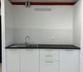 a compact kitchen with a single stainless steel sink and three cabinets
