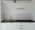 Modern kitchen with white cabinets, black countertops, stainless steel sink, and silver faucet.