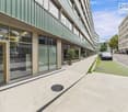 Modern office building with glass facades, entrance doors, and a ground floor raised above street level.