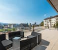 outdoor furniture, potted plants, glass railing, view of the city