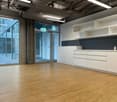 Open and empty kitchen with large windows, bamboo flooring, modern cabinetry, stainless steel faucet