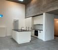 White kitchen with large countertop, black countertops, built-in oven, minimalist design, cement floor, modern fixtures, glass windows