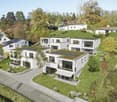 Multi-story apartment building with white exterior, green roofs, balconies, and surrounded by landscaped gardens and trees