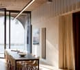 Dining room with long table, chairs, wooden floor, glass doors, projector, curtains