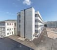 Modern architecture office building, white exterior, multiple floors, structured parking lot, multiple windows