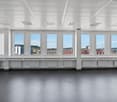 Modern office space with large windows, white walls, ceiling lights, and city view