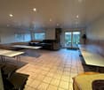 large open room with tables, chairs, and windows, fireplace, kitchen area, and sliding glass doors