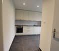 modern kitchen with white cabinets, black tiled floor, integrated oven and dishwasher, sink with faucet