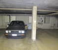 underground parking space with concrete walls, pillar, ceiling with beams, electrical boxes, one car parked