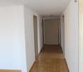 Empty hallway with wooden floors, white walls, and doors on both sides.