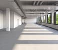 Open corridor, white walls, concrete floor, large windows, sunlight from windows