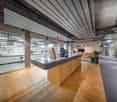 modern office space with a kitchen island, large glass walls, pendant lighting, wooden flooring, appliances, plants