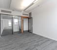 modern office space, sliding glass doors, wooden door, gray flooring, white walls, central lighting