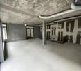 A room with grey walls and flooring, a staircase, and pipework
