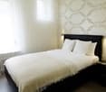 spacious bedroom with double bed, white linens, white curtains, patterned wall, white walls, large window