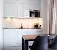 white cabinetry, wooden countertop, black chairs, sink, electric kettle, microwave
