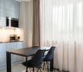Modern kitchen with a table and two chairs, cabinets, sink, built-in microwave, and coffee machine.