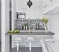 modern kitchen with white cabinets, gray countertop, pendant light, microwave, coffee machine, yellow flowers, green apples