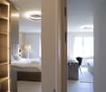 Modern bedroom with bed, built-in wardrobe, desk, lamps, and windows