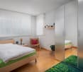 Bedroom with bed, chair, nightstand, shelf, potted plant, and closet