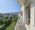Balcony with a view of the surrounding neighborhood, including houses, trees, and mountains in the distance.
