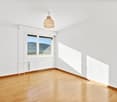 Spacious bedroom with large windows offering a scenic view, hardwood flooring, and a wooden pendant light fixture.