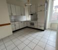 Spacious L-shaped kitchen with white cabinets, tiled floor, and a dishwasher