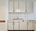 Modern, sleek kitchen with white cabinetry, stainless steel appliances, and tiled backsplash.