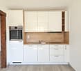 Modern kitchen with white cabinets, wooden countertop, built-in oven, and dishwasher
