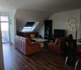 wooden floors, beige walls, two couches, center table, television, bookshelves, attic with window, lamp, table and chairs, entrance with glass door