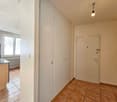empty room with tile flooring, white walls, two doors, window with radiator, corner cabinet, lamp